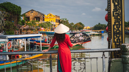 A woman in traditional Vietnamese cultural clothing in the ancient city of Hoi An on a bridgeの写真素材