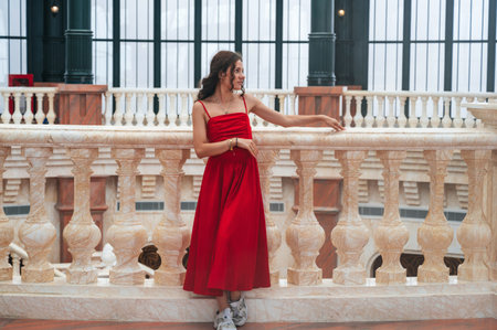 A romantic female tourist stands gracefully in a red dress.の写真素材