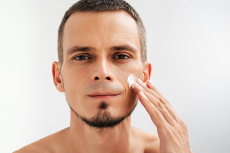Detail shot of a man using cosmetic cream for facial care.の写真素材