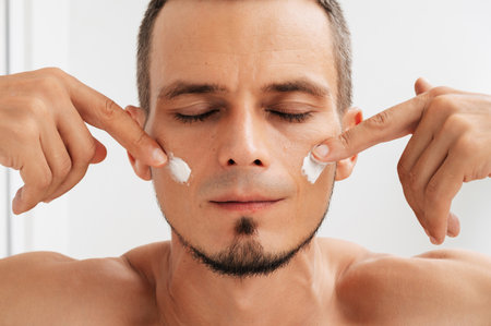 A detailed shot of a man applying moisturizer to his face.の写真素材
