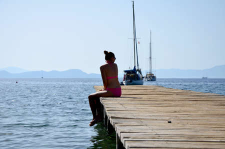 Young woman on a wooden wharf for small yachtsの写真素材
