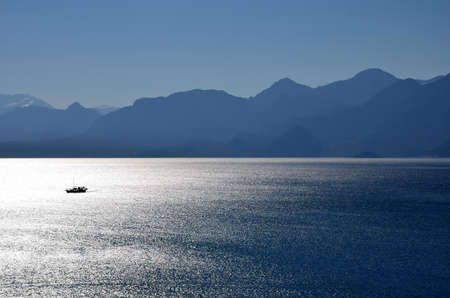 Lonely small boat floats in the sea at duskの写真素材