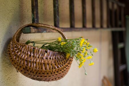 Wicker basket with wildflowers hanging on the wooden ladder, old cottageの写真素材