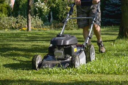 Man cutting grass the lawn mower, powerful petrol lawn mower in sunlightの写真素材