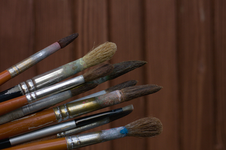 Assorted dirty old painting brushes, wooden backgroundの写真素材