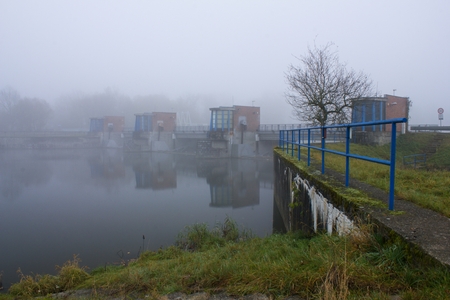 Old water dam on the river in the morning mist. Autumn fog over the river weir.の写真素材