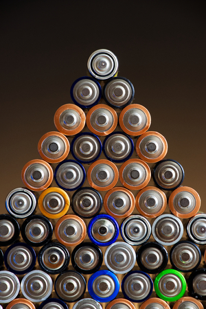 Many different colored AA batteries Arranged in a pyramid on a dark gradient backgroundの写真素材