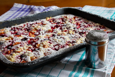 fruitcake and metal sugar bowl on wooden table, sugared fruit pie on baking tray, kitchen towelsの写真素材