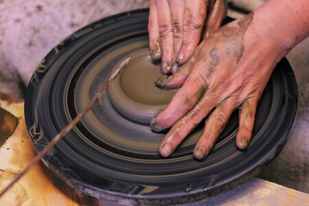 Closeup of hands working on pottery wheel, clay potの写真素材