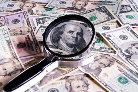 US currency, dollar bill under a magnifying glass as a symbol of financial investigations of corruptionの写真素材