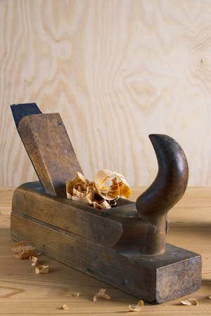 Old plane on wooden board, carpentry tools with wood shavings and sawdust, wooden background