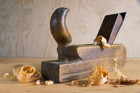 Old plane on wooden board, carpentry tools with wood shavings and sawdust, wooden backgroundの写真素材