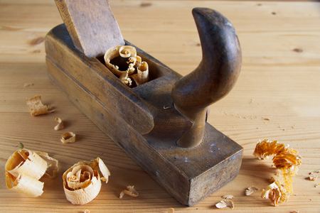 Old plane on wooden board, carpentry tools with wood shavings and sawdustの写真素材