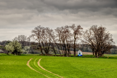 Santa Barbara chapel landscape at spring, South Moravia, Czech Republic. Chapel in a field surrounded by trees with dramatic cloudy skies. High dynamic range.の写真素材