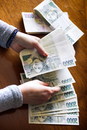 Woman counting money. Czech currency in banknotes. Bundles of paper bills on the table.の写真素材