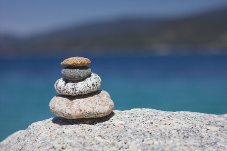Relax Zen stones. Background sea for the perfect meditation. Stones pyramid in the sun, coast in the distance.の写真素材