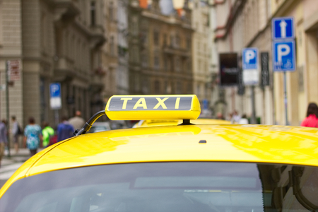 Taxi car in the city street of Prague, Czech Republic. A symbol of taxi service on the roof of a yellow car.の写真素材