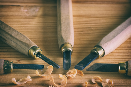 Carpentry tool concept. Small chisels on a wooden board with shavings. Work with wood. の写真素材