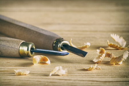 Carpentry tool concept. Small chisels on a wooden board with shavings. Work with wood. の写真素材