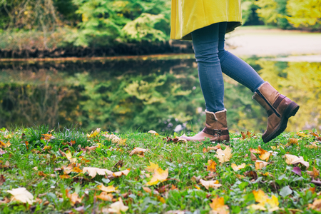 woman in leather boots is walking in an autumn park next to a lake, tourist girl, leisure time in a nature.の写真素材
