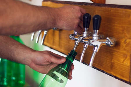 Man pouring wine into a plastic bottle, wine bottling plant. Waiter serves in the tavern. の写真素材