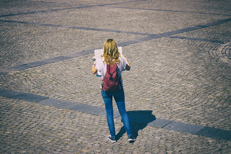 A tourist girl lost herself in the historic european city. Travel concept with woman holding a map.