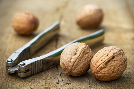 walnuts and a nutcracker on a wooden board, old metal nutcrackerの写真素材