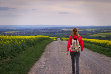 Traveler woman is walking on the road alone after sunset. Long way to go, travel conceptの写真素材