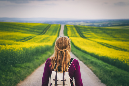 Long way to go. Woman travelling in countryside. Tourist standing on the road. Travel concept. Challenge of journeyの写真素材