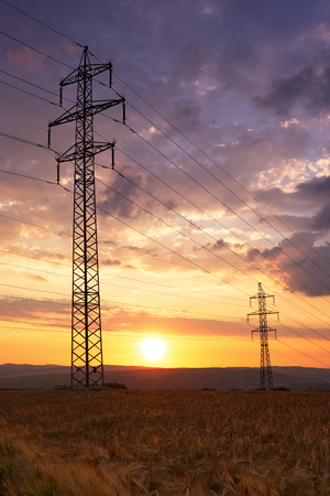 Sunset behind electricity pylons. Dramatic sky and electric power lines during sunset.の写真素材
