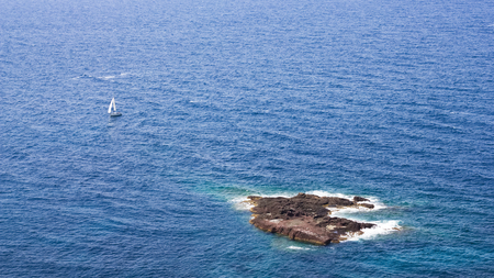 Aerial view to Sardinia coastline with sailing boat in distance. Yacht on open seaの写真素材