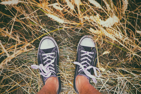 Man wearing black and white sneakers and standing in golden wheat field. Enjoying summertimeの写真素材