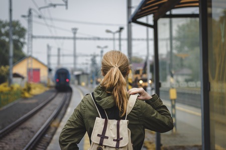 Woman with backpack is looking at the departing train. Travelling during autumn season. Travel conceptの写真素材