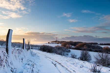 Snowy winter landscape with telecommunication tower in distance during sunset. Winter season in natureの写真素材