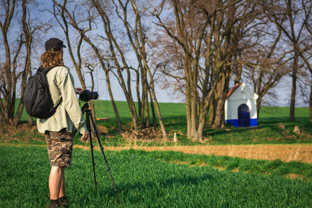Photographer taking picture of Santa Barbara chapel in Moravian Tuscany, Czech Republic. Man with camera and tripod in natureの写真素材