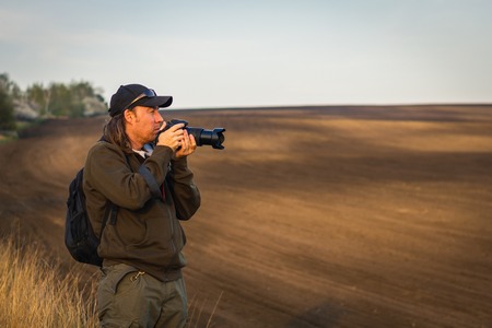 Photographing rural scene during golden hour. Man with camera outdoors. Photographer in Moravian Tuscany, countryside of Czech Republicの写真素材