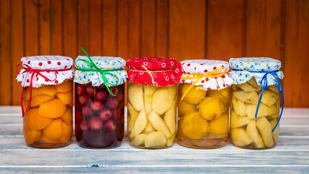 Fruit compote in jar, homemade preserved food. Variety of canned fruits on wooden table. Organic food concept.の写真素材