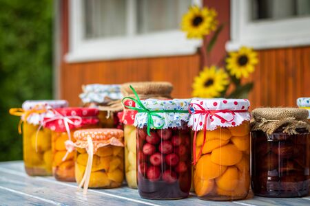 Variety of diferent fruit compote in jar. Homemade preserved food on table. Peach, apricot, cherry, apple, pear and plum compotesの写真素材