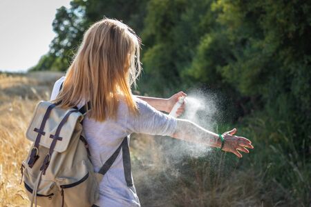 Woman tourist applying mosquito repellent on hand during hike in nature. Insect repellent. Skin protection against tick and other insect.の写真素材