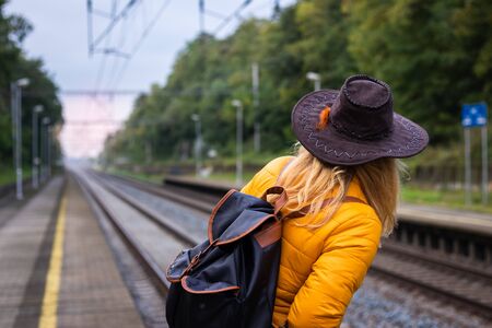 Traveler waiting at railroad station for train. Woman with backpack and hat is looking out train at platform. Travel conceptの写真素材