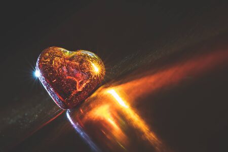 Shiny heart crystal in dark background with copy space. Transparent gemstone and bright reflection. Heart jewel as a symbol of love or valentines dayの写真素材