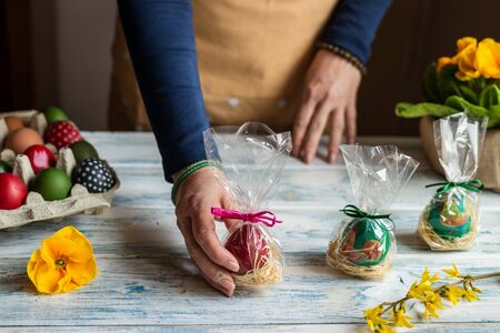 Woman holding wrapped easter eggs as gift for Easter holiday celebration. Making decoration at homeの写真素材