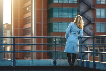 Beautiful woman relaxing at terrace and looking to cityscape. Fashion businesswoman enjoying view to...