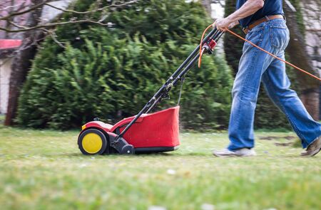 Gardener verticutting the lawn at spring. Panning shot of verticutter, walking legs in motion blurの写真素材