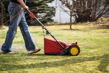 Gardener verticutting the lawn at spring. Panning shot of verticutter, legs in motion blurの写真素材