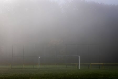 Empty soccer goal post in fog. Football pitch in mist. Sport soccer field outdoorsの写真素材