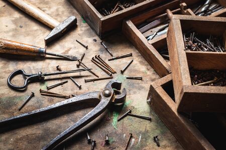 Vintage work tool and toolbox on wooden table. Pliers, hammer, screwdriver, bolt, screw and other hand tools in workshopの写真素材
