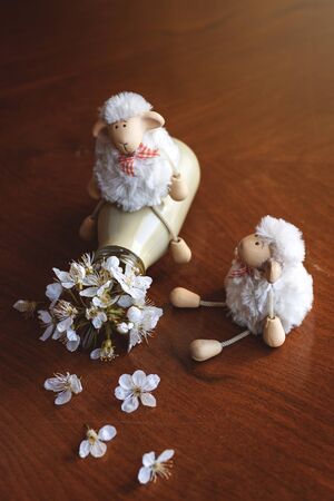 What have you done? Funny sheep toys playing with colorful bottle and flowers. Humor concept about springの写真素材