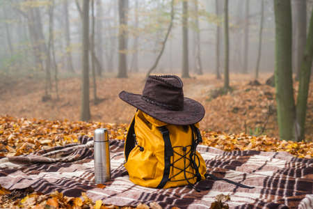 Hiking equipment. Backpack,   hat on picnic blanket in autumn forest. Camping in natureの写真素材