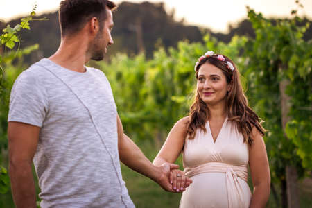Follow me on journey of life. Pregnant woman holding hands with her partner. Young couple outdoorsの写真素材